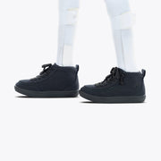 A person wears white leg braces and socks with BILLY Footwear's Black to the Floor BILLY Classic D|R II High sneakers. These black high-tops have black soles and a wide toe box, making them AFO-friendly. Shown on a plain white background.